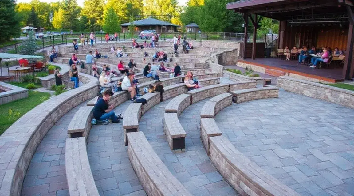 Curved stone seating steps facing a small stage in a park